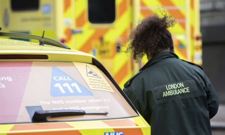 A paramedic is seen near ambulances, parked on the street, in London