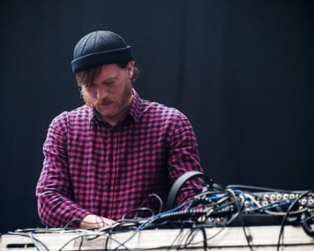 A man in a beanie hat DJing at a festival