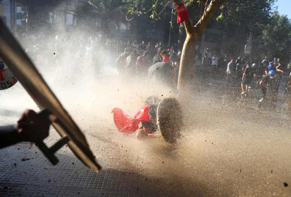A demonstrator takes cover behind a makeshift shield during an anti-government protest in Santiago, Chile, 15 November