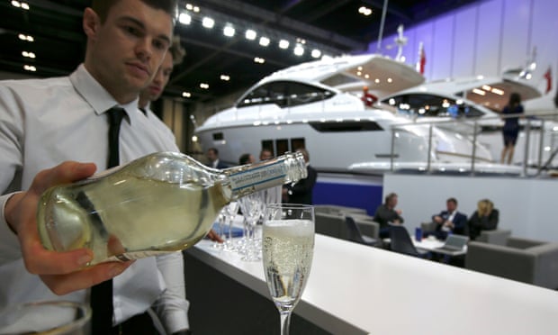 A waiter pours a glass of sparkling wine at a display of luxury yachts, at the London Boat Show