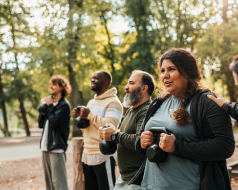 A group of people walk outdoors with backpacks on a tree-lined path
