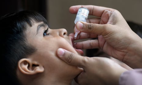 A health worker administers polio vaccine drops to a child
