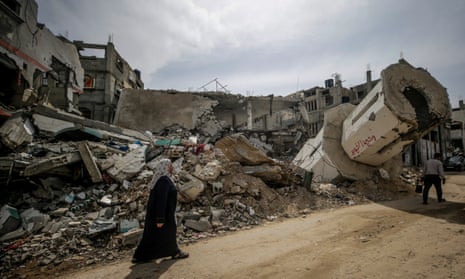 A Palestinian woman walks past the rubble of a destroyed mosque after Israeli air strikes in al-Maghazi refugee camp, southern Gaza, on 29 March.