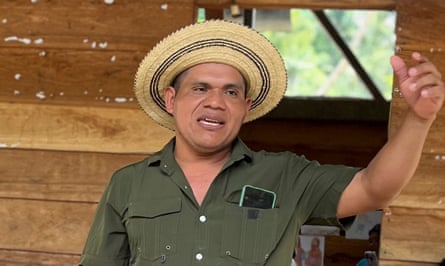 A man in a green shirt and straw hat gestures during a speach.