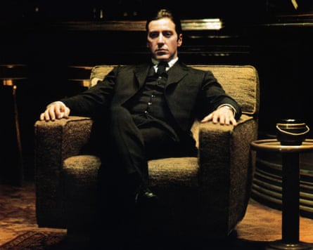 Pacino as Michael Corleone in a black suit sitting in a dark room