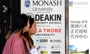People walk past signage for Australian universities in Melbourne’s CBD.