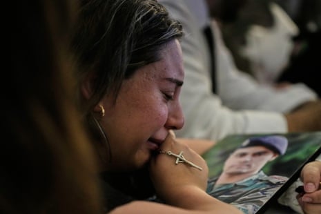 Rozette, esposa do capitão do exército libanês Elie Khoury, morto em um ataque aéreo israelense, chora tanto diante de seu retrato quanto segura uma cruz.