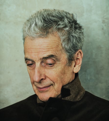 Peter Capaldi, head and shoulder shot, in three-quarter profile and looking down; wearing a black blazer, collar turned up