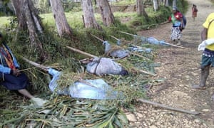 Women wave branches away from the bodies of people killed in Karida village, an act of courage given that most from the village fled for fear the violence would restart.