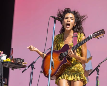 Olivia dean holds guitar and sings on stage