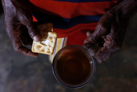 A man holds biscuits and a cup of tea