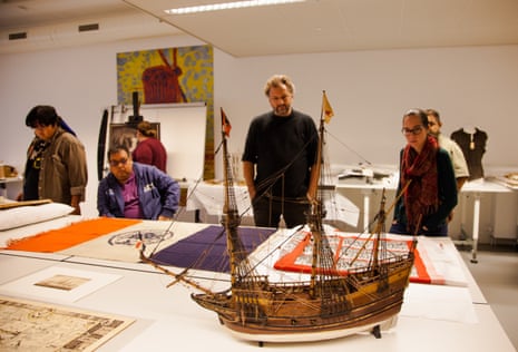 A moel ship is examined by people in a museum