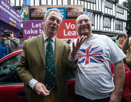 Nigel Farage në këmbë me një mbështetës të Brexit me një 'Voto largohu' dhe pankarta të tjera në sfond