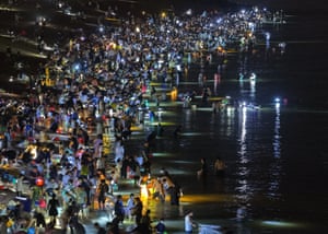 A crowd of people wading into the sea at night