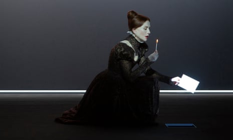 Huppert, in severe black, holds a lit candle and a letter