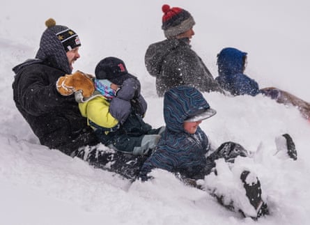 parents and three kids sled in snow
