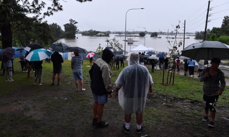 Onlookers watch the submerged New Windsor Bridge at Windsor in the north west of Sydney, Monday, March 22, 2021.