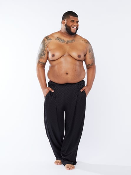 A large, bare-chested Savage x Fenty male model in trousers