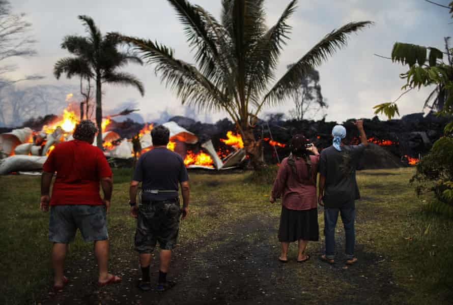 Community members watch as a home is destroyed by lava from a Kilauea volcano.
