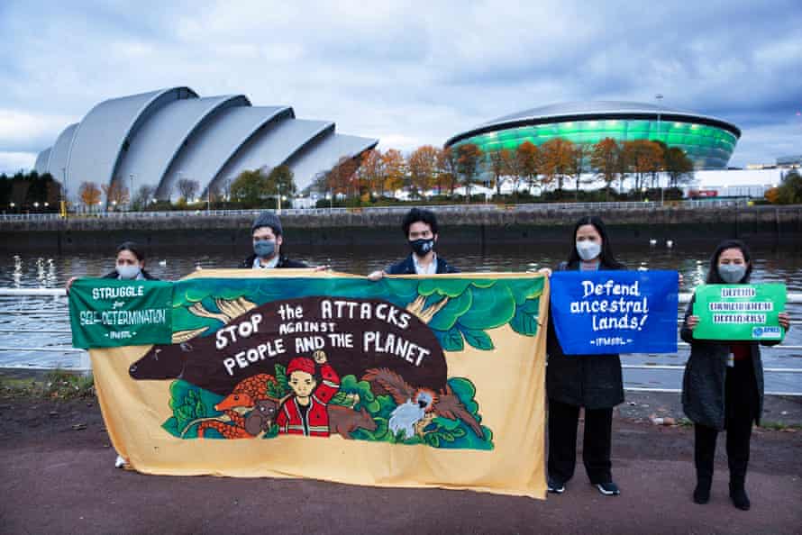 Activists in Glasgow holding signs that say 'stop the attacks against people and the planet' and 'defend the ancestral lands'