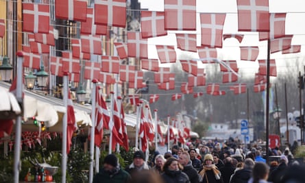 People walk under Danish flags in Copenhagen city centre