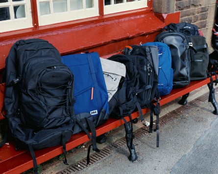The rucksacks lined up and ready for testing on a red railway bench