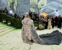 A woman in a sparkly dress with a skeleton cutout and a long feathered cloak walks toward a staircase