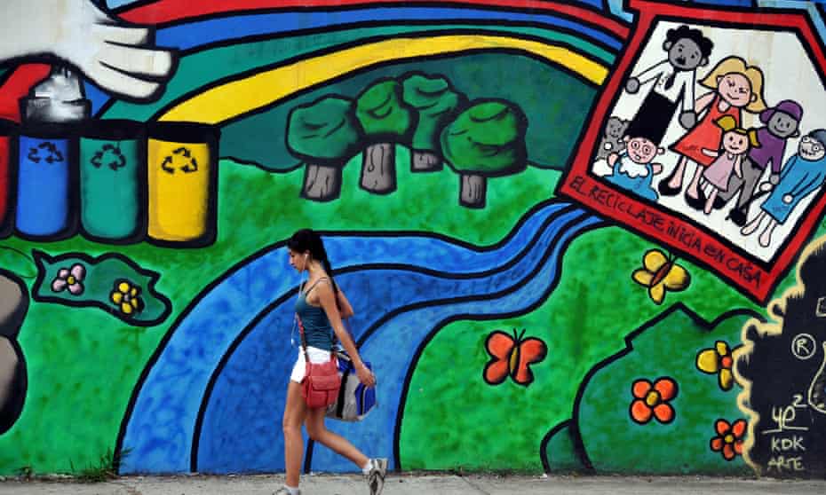 A Costa Rican girl walks past a mural in favor of recycling and the environment on a street of San Jose,