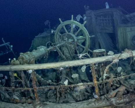 The ship's wheel and the stern of the Endurance seen intact under the sea with different creatures on the rails, chains and cables