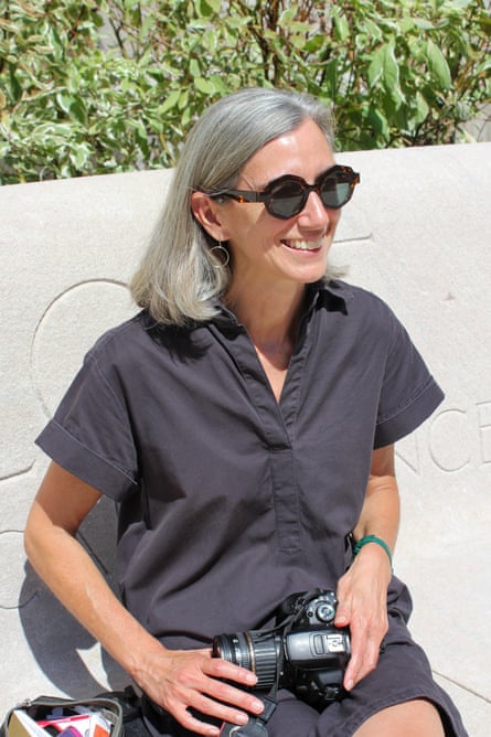 a woman smiles while sitting with a camera in her lap