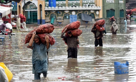 Labourers carry vegetable sacks as they wade through flood water after heavy monsoon rain in Lahore, Pakistan.