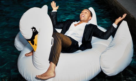 John Legend lying back, arms open, on an inflatable swan