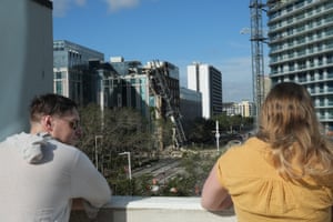 people look out at a collapsed crane and damaged building