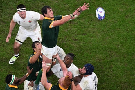South Africa's lock Franco Mostert (C) stretches to catch the ball as he is lifted into the air for an England lineout.