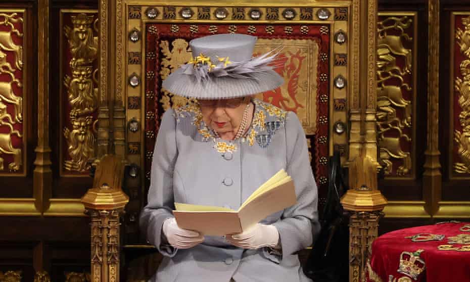 Queen Elizabeth wearing a mauve coat and hat reading the speech from a booklet