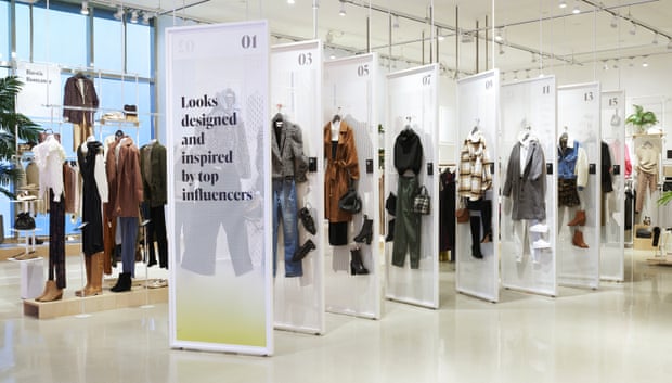 Clothes are displayed on white grids in a well-lit store.  a sign says 