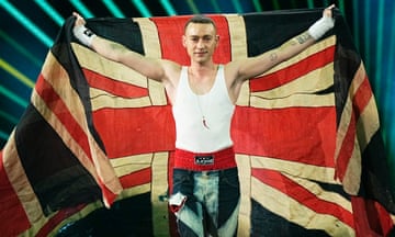 Olly Alexander, wearing a white vest, holds a union flag