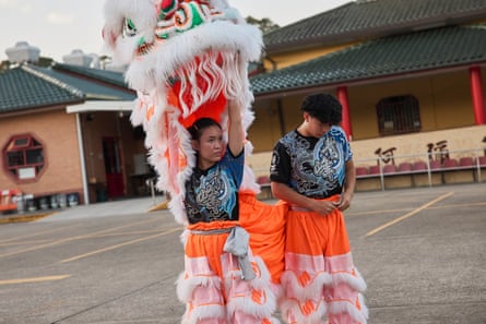 Dance team instructor Adelene Pham holds her lion head aloft as the other part of the lion, Dylan Kha fastens his costume