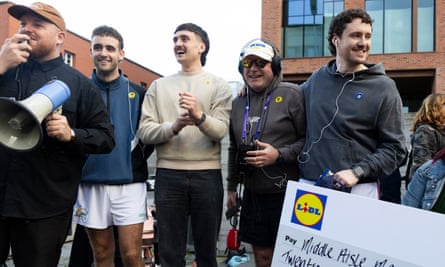 Three Paul Mescal lookalikes standing on a podium with two members of event staff.
