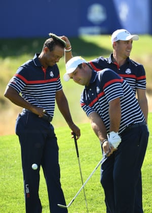 Tiger Woods smiles as Justin Thomas places a tuft of turf on his head as Patrick Reed plays a shot.