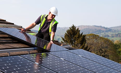 An engineer fits solar panels to a house in Wales