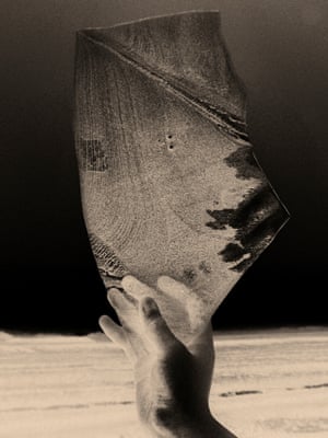photo negative image of a hand holding broken glass