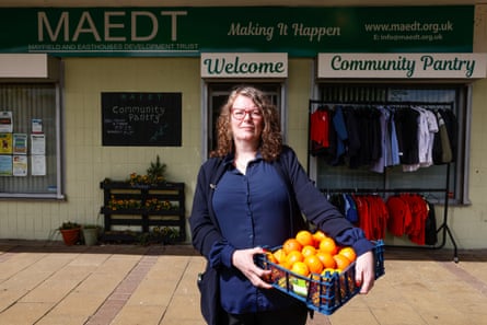 Sharon Hill holds a basket of fruit and stands in front of a building