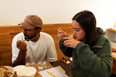 Two people at a table, sampling sauerkraut.
