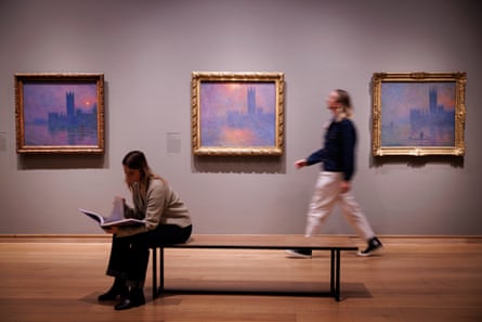 Two people pose with Monet paintings of the Houses of Parliament at the Courtauld Gallery.