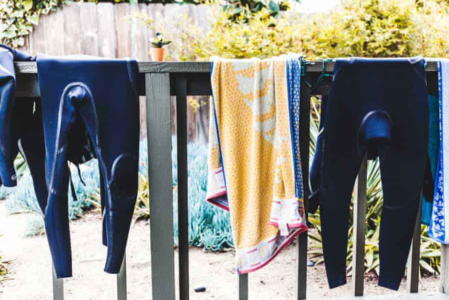 Wetsuits hanging by the waist over a balcony rail