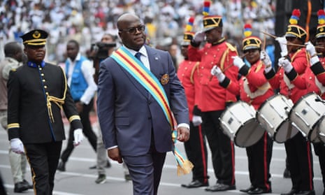 Felix Tshisekedi walks past a line of military personnel playing drums and saluting