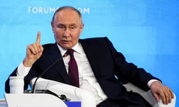 Russian leader Vladimir Putin, wearing a suit, gesticulates during a conference.