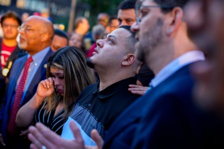 A teary-eyed man looks up next to a crying woman at a vigil