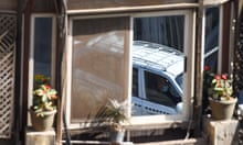 An apartment window in Zamalek, Cairo Egypt reflects a passing white taxi